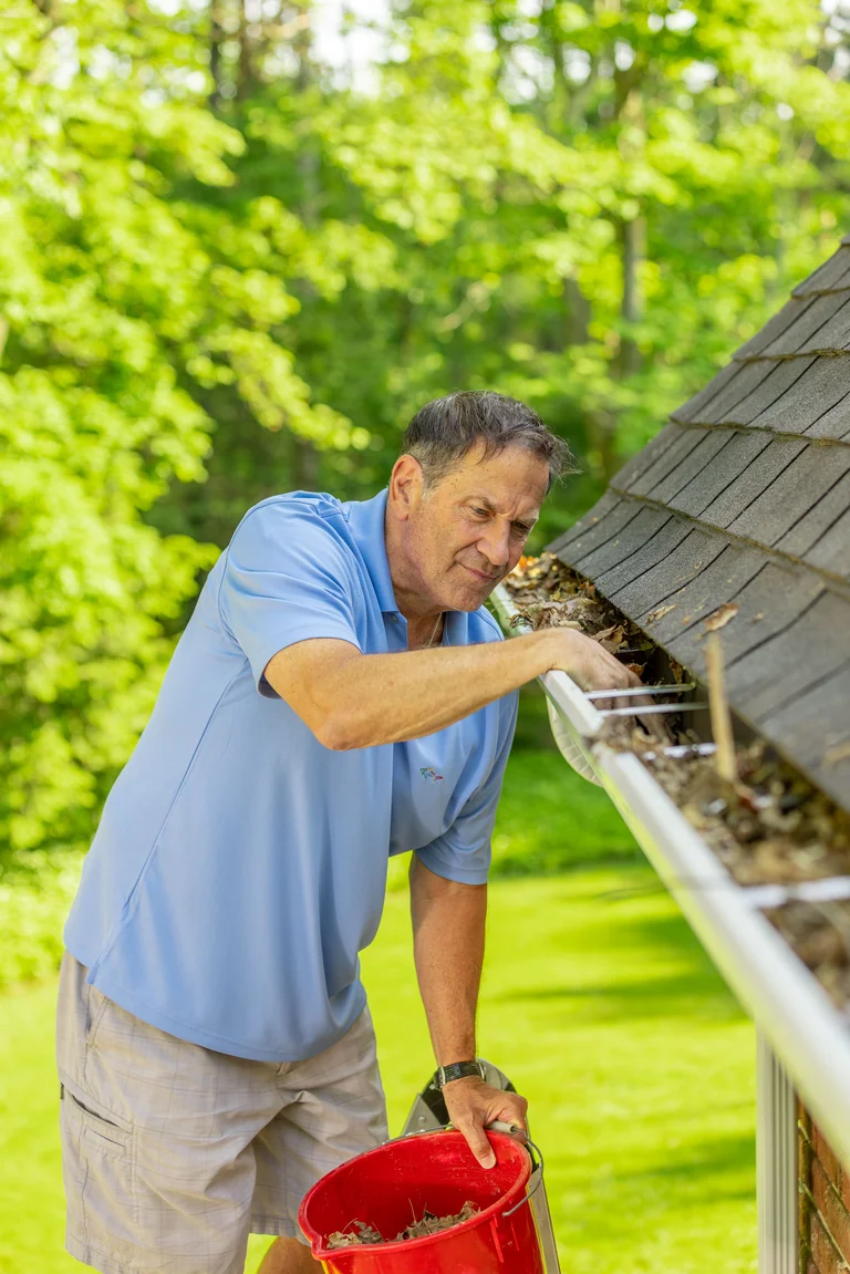 DIY Homeowner cleaning gutters from a ladder in Akron