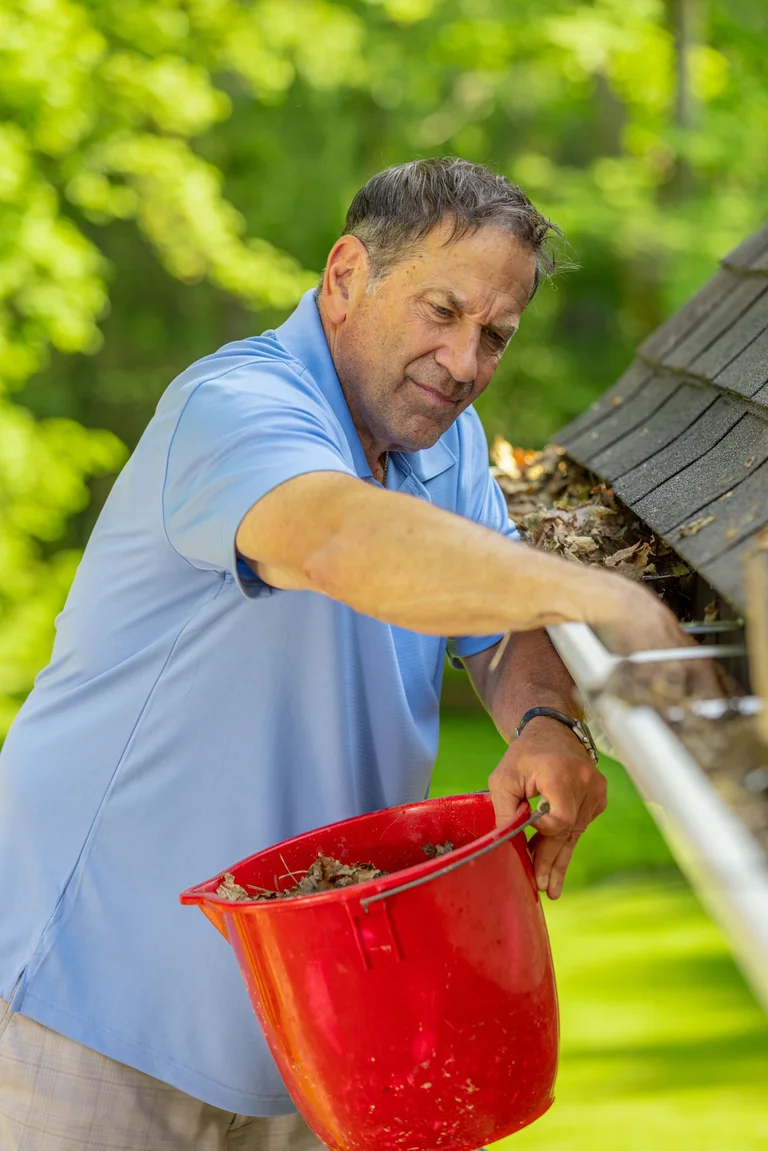 DIY Homeowner cleaning gutters from a ladder in Athens