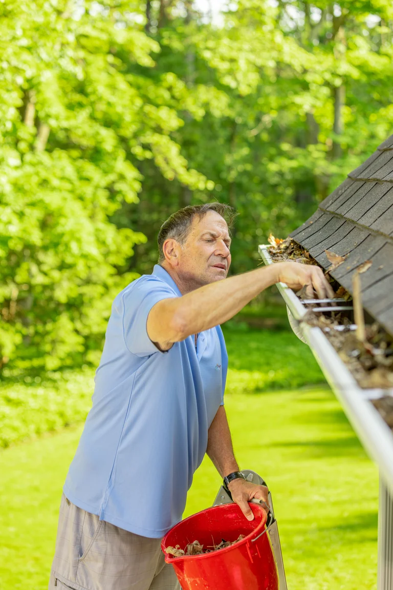 DIY Homeowner cleaning gutters from a ladder in Boise